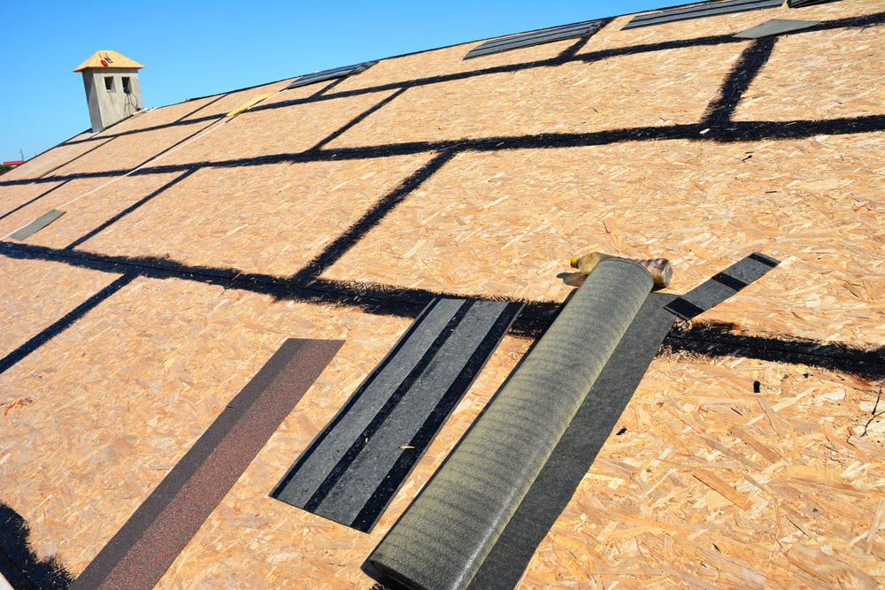 Roofing construction. Preparing a osb roof deck with bitumen waterproofing in cracks before underlayment, felt paper and asphalt shingles installation.